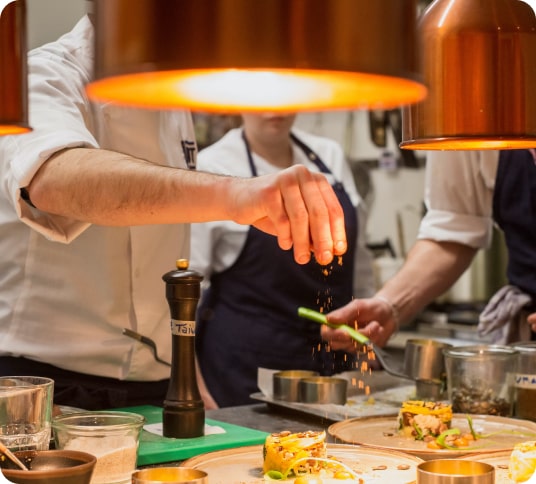 chefs in the background sprinkling herbs as the final touches to a dish